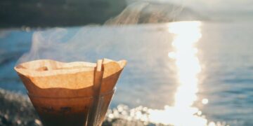 turkish coffee brewing on pebbles and morning sun reflecting in the sea